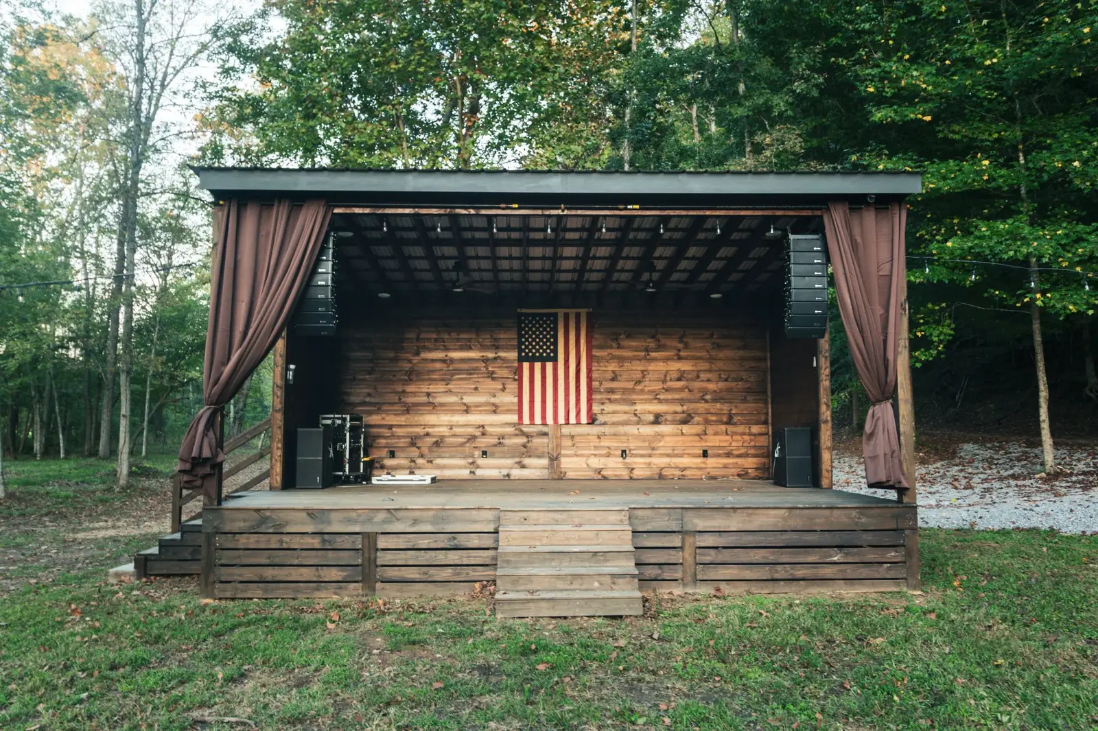 Concert stage at Song House Drive with American flag, PA system, and stage curtains