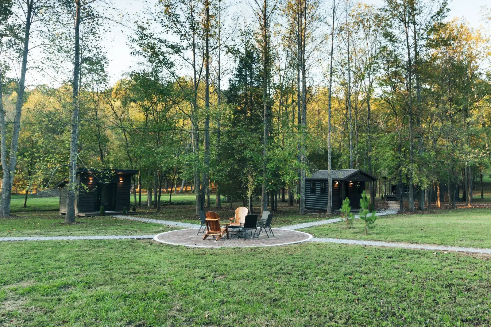 Fire pit area with Adirondack chairs and cabins in the woods
